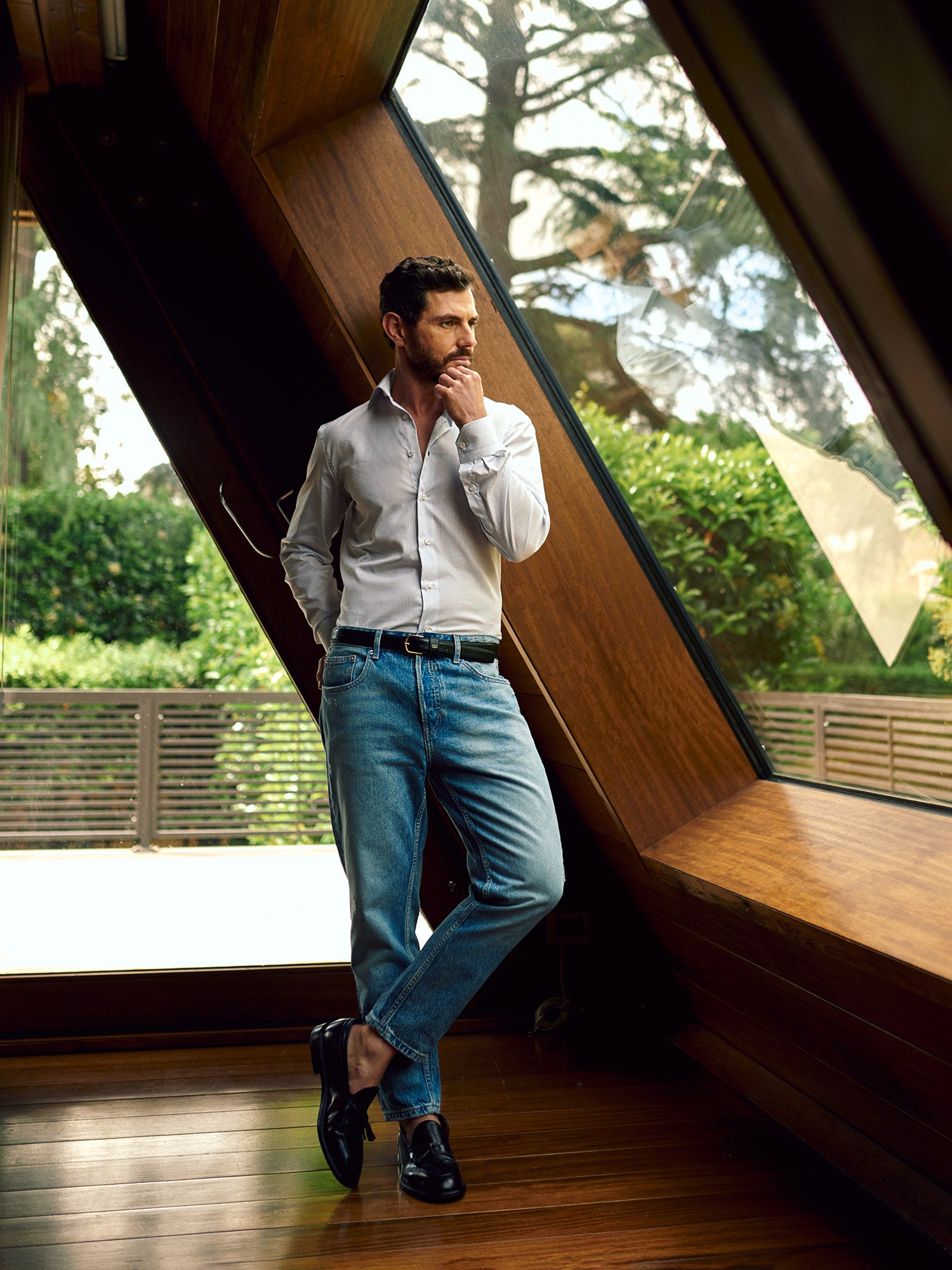 Modello Agenorie in camicia sartoriale bianca, in posa in un interno di design